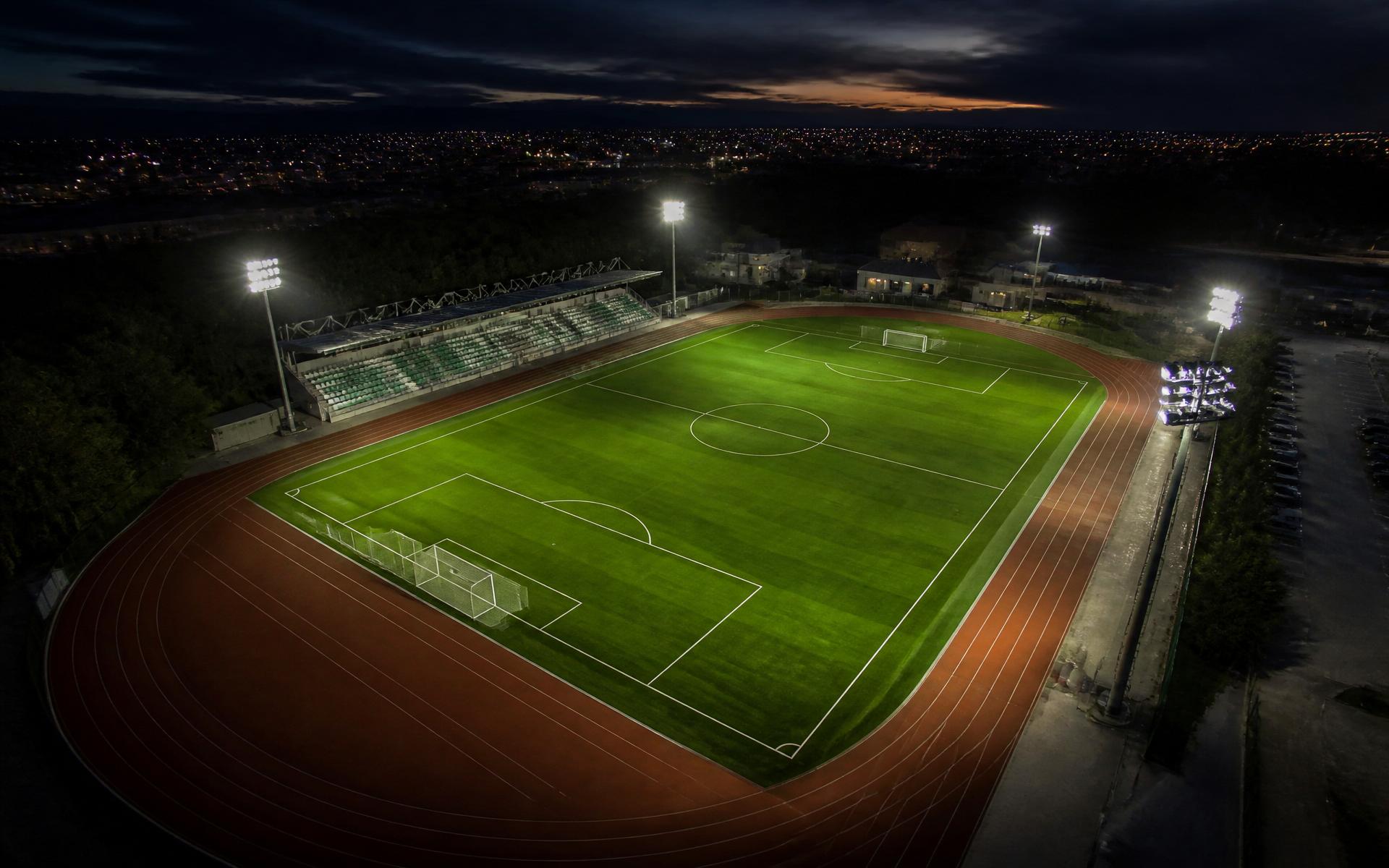 Aerial view of a floodlit synthetic football pitch at dusk